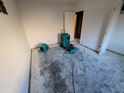One dehumidifier and a single air mover standing on a bare floor after flooring removal