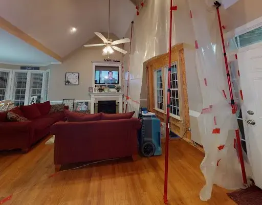 Containment walls, a dehumidifier and air movers drying a Weston living room behind plastic sheeting