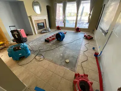 Air movers beside a dehumidifier in a Weston living room, running after wet carpet was lifted